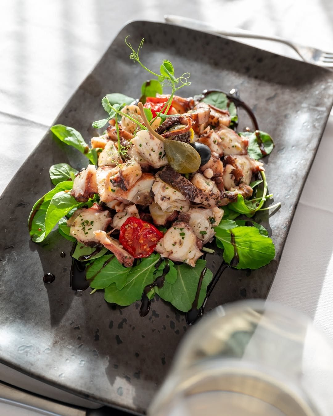 Salata od hobotnice s rukolom, kaparima i balsamicom uz čašu bijelog vina